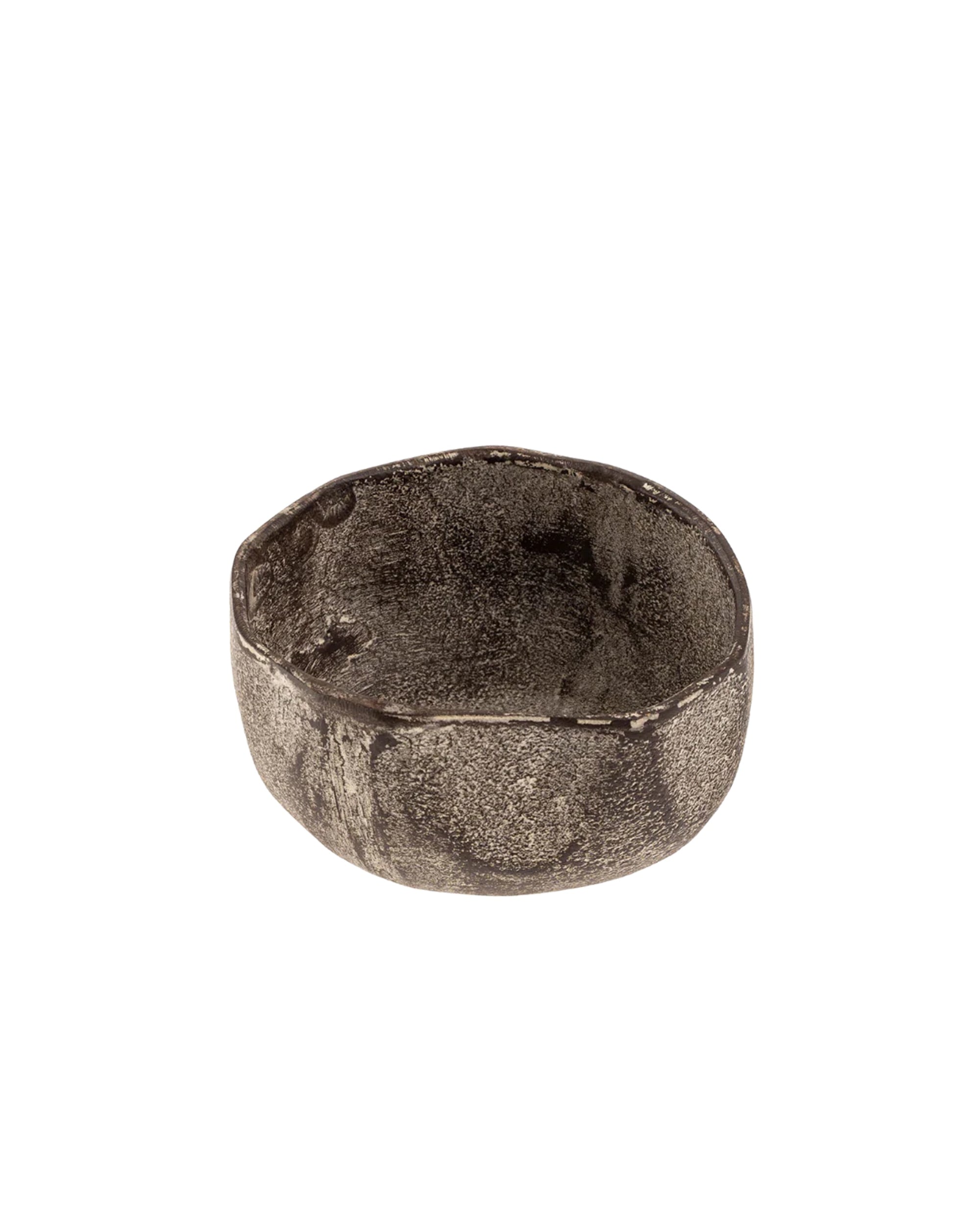 The Indaba 1-0882 Rustica Bowl S is a small, round, shallow aluminum bowl with a textured, uneven dark finish. Handcrafted in India using sand casting, it features a rustic, stone-like look and artisan appeal.