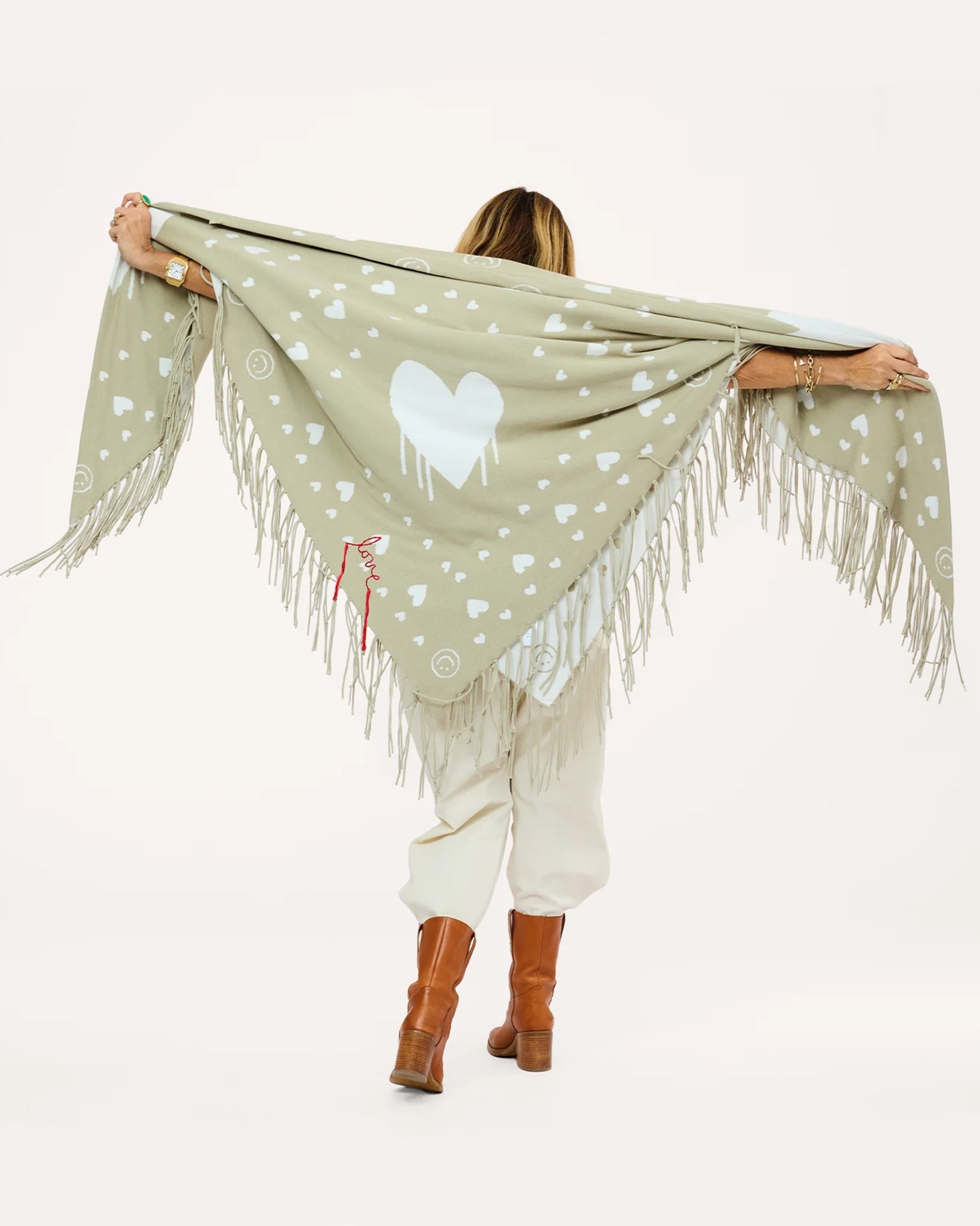 Cotton knit poncho with drippy heart design by Kerri Rosenthal, shown from the back, styled with boots.