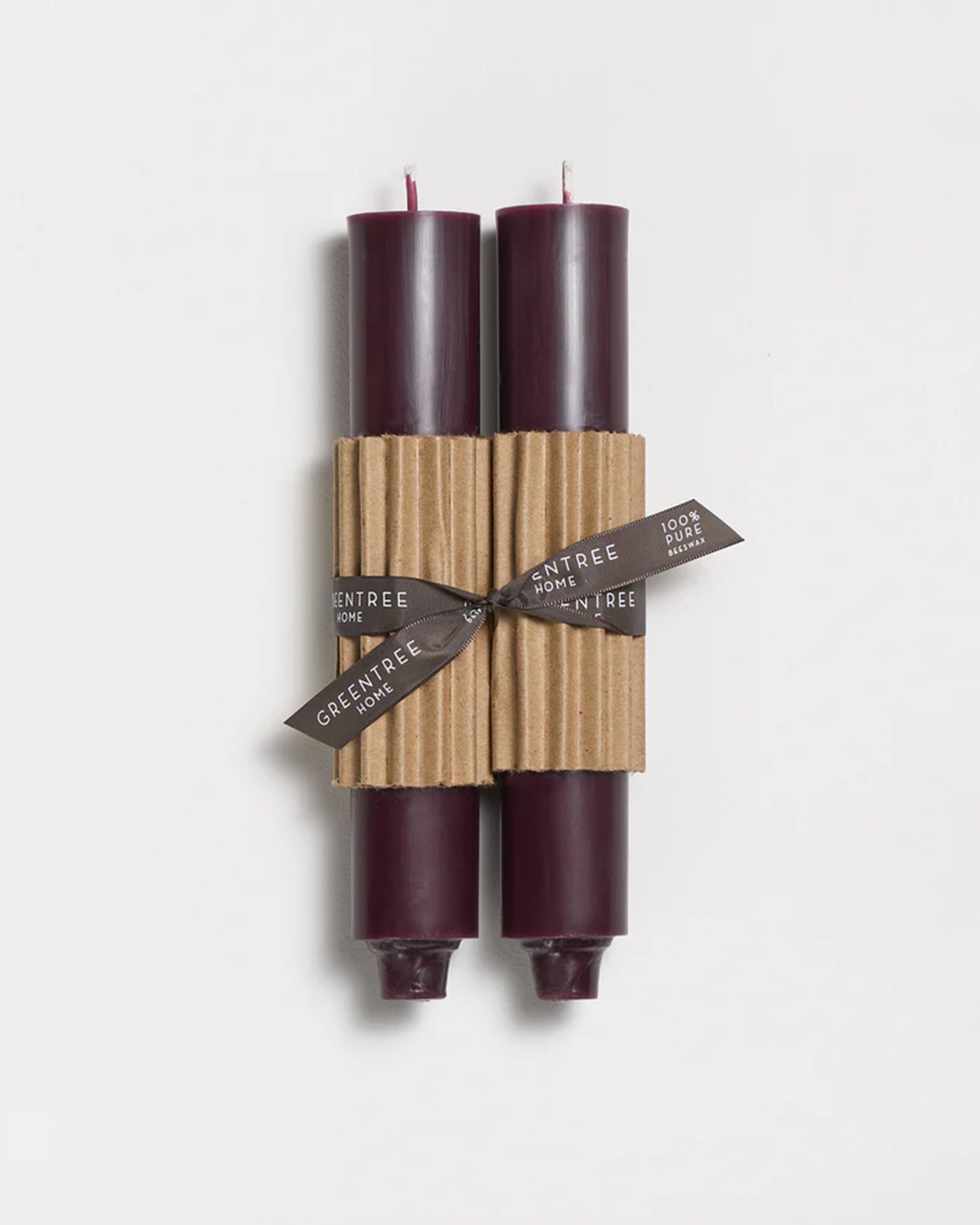 A pair of Faire 9" Taper Candle/Sangria, hand-poured for a smooth finish, are bundled with a ribbed brown sleeve and black ribbon, shown on a white background.