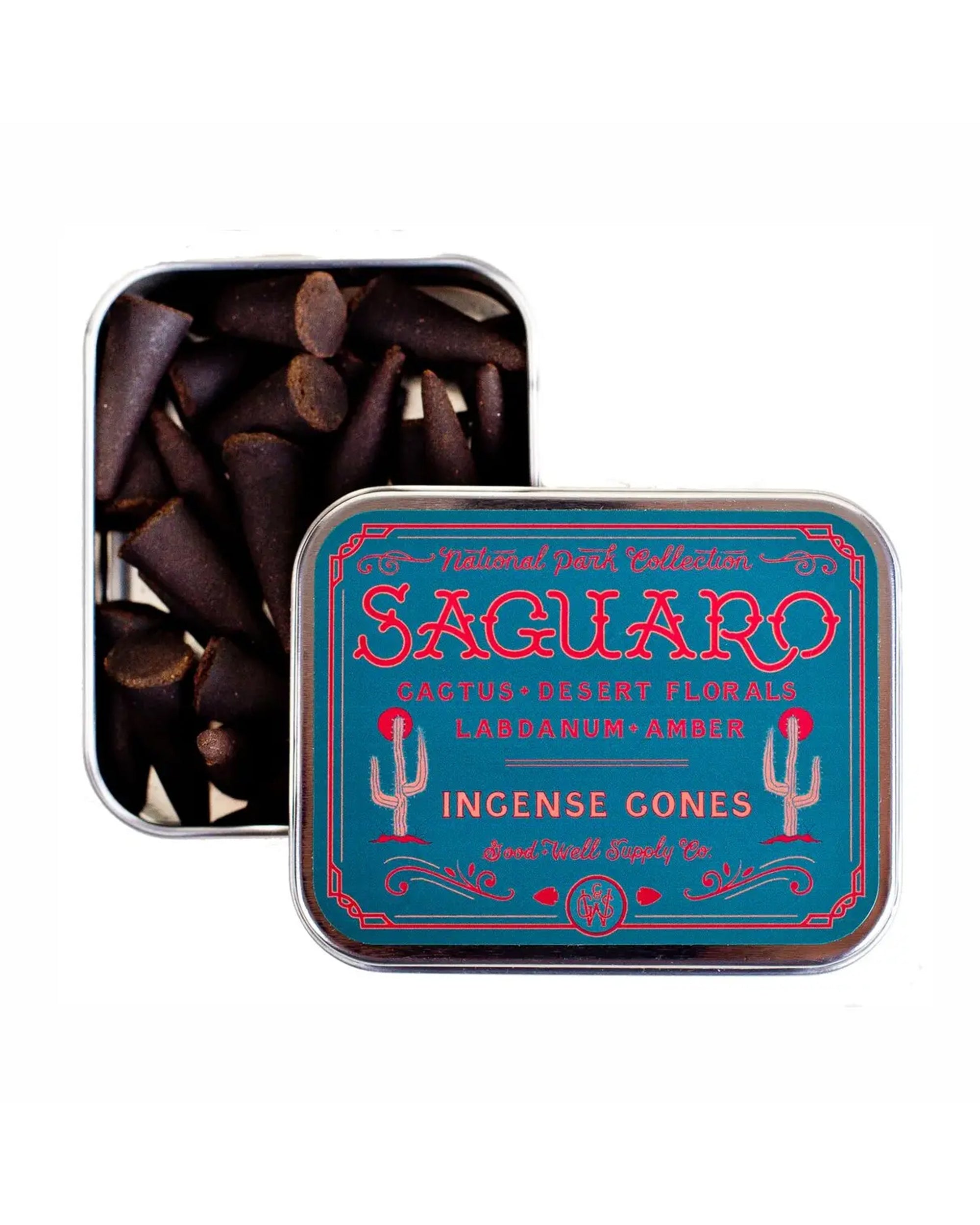 A rectangular metal tin labeled "Saguaro Incense" by Faire, featuring cactus flower and floral designs, holds dark brown incense cones. The partially open lid displays the aromatic cones inside.