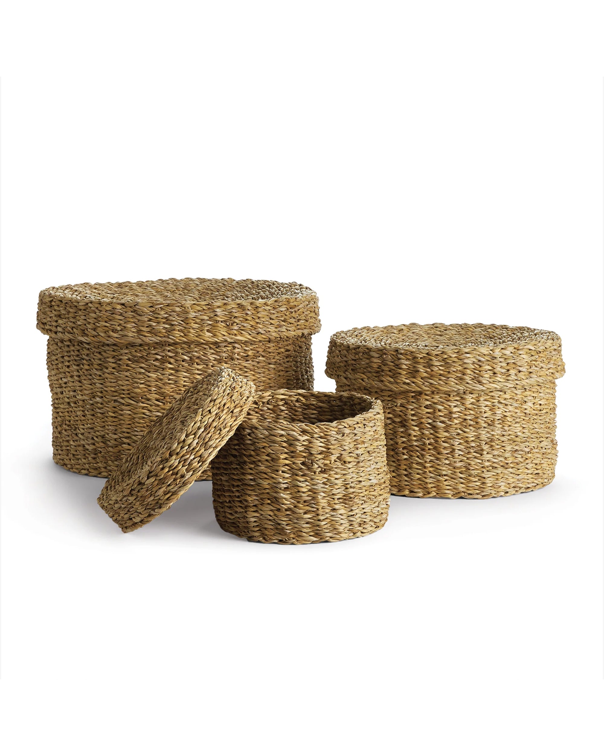 The Napa Home & Garden Seagrass Round Lidded Baskets feature three natural, wicker-look baskets—two with lids and one open to show its spacious interior—perfect for versatile storage and stylish organization.