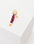 The Upside's LIMITLESS KEYRING features a gold keychain with a star charm, a red braided polyester cord, and two small orange beads, all displayed on a white block.