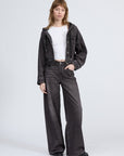 A person with straight light brown hair and bangs wears the Rag & Bone miramar terry hood trckr jckt, matching wide-leg jeans, a white crop top, and black shoes against a plain background for an effortless Miramar-inspired look.