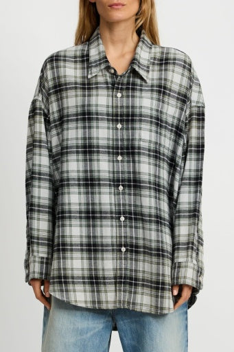 A person wearing a loose-fitting Denimist BUTTON FRONT SHIRT PLAID with long sleeves and light blue jeans stands against a plain white background.