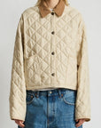 A person wears the Denimist FAULKNER QUILTED JACKET in cream with a brown collar and blue jeans, standing against a plain white background.