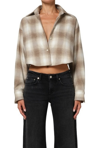 A person wears the Citizens Of Humanity/AGOLDE ana cropped shirt in schiffer plaid, a brown and beige collared button-up styled unbuttoned at the top, paired with wide-leg black jeans. The person's head is not visible.