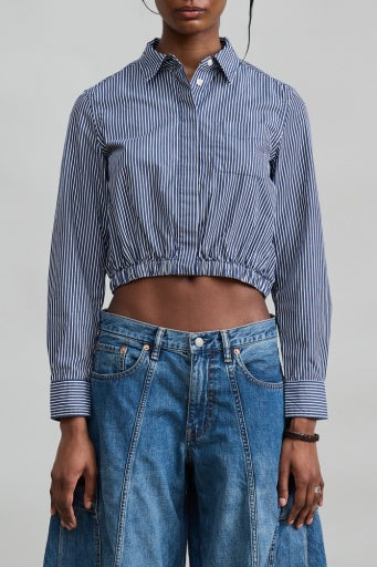 Denimist cropped elastic waist shirt paired with high-waisted jeans, styled in a minimal modern setting.