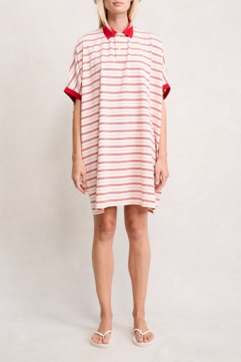 A person wearing the Denimist POLO SHIRT DRESS—loose-fitting with short sleeves, a spread collar, and red and white stripes—stands in white sandals against a plain background.