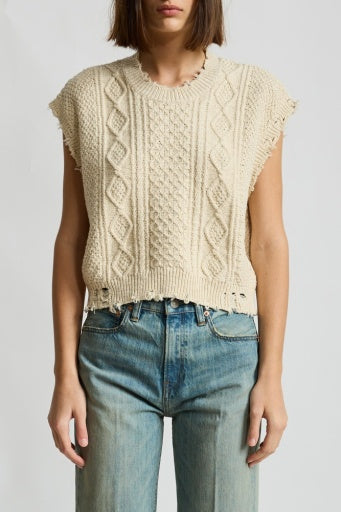 A person wears the Denimist BOYFRIEND CABLE VEST, a sleeveless cream knit, paired with high-waisted blue jeans, standing against a plain light background.