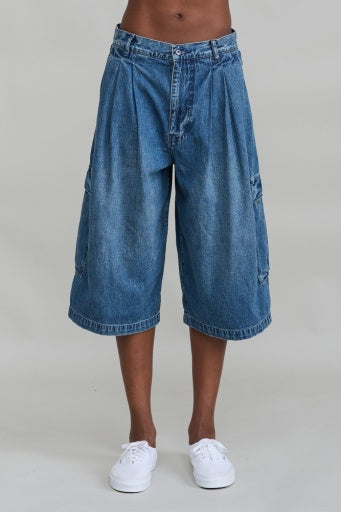 Denimist Ainsley Triple Pleat Cargo Short in light fabric, paired with white sneakers, waist to knees, plain background.