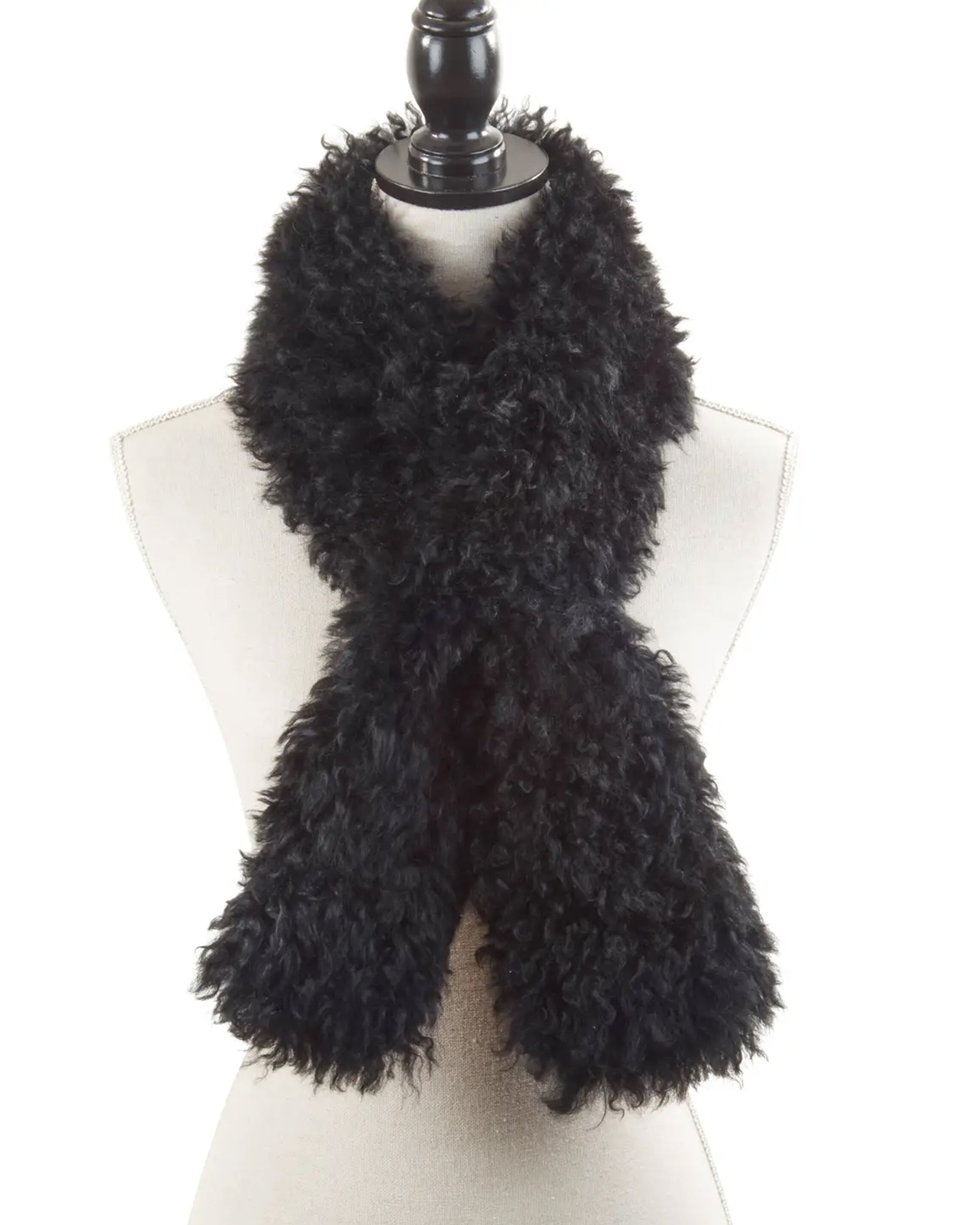 A mannequin showcases the Faire Lamb Fur Pull Through scarf, its fluffy black fur crossed in front for a cozy, stylish look. The plain white background highlights the luxurious warmth and chic texture of this elegant accessory.