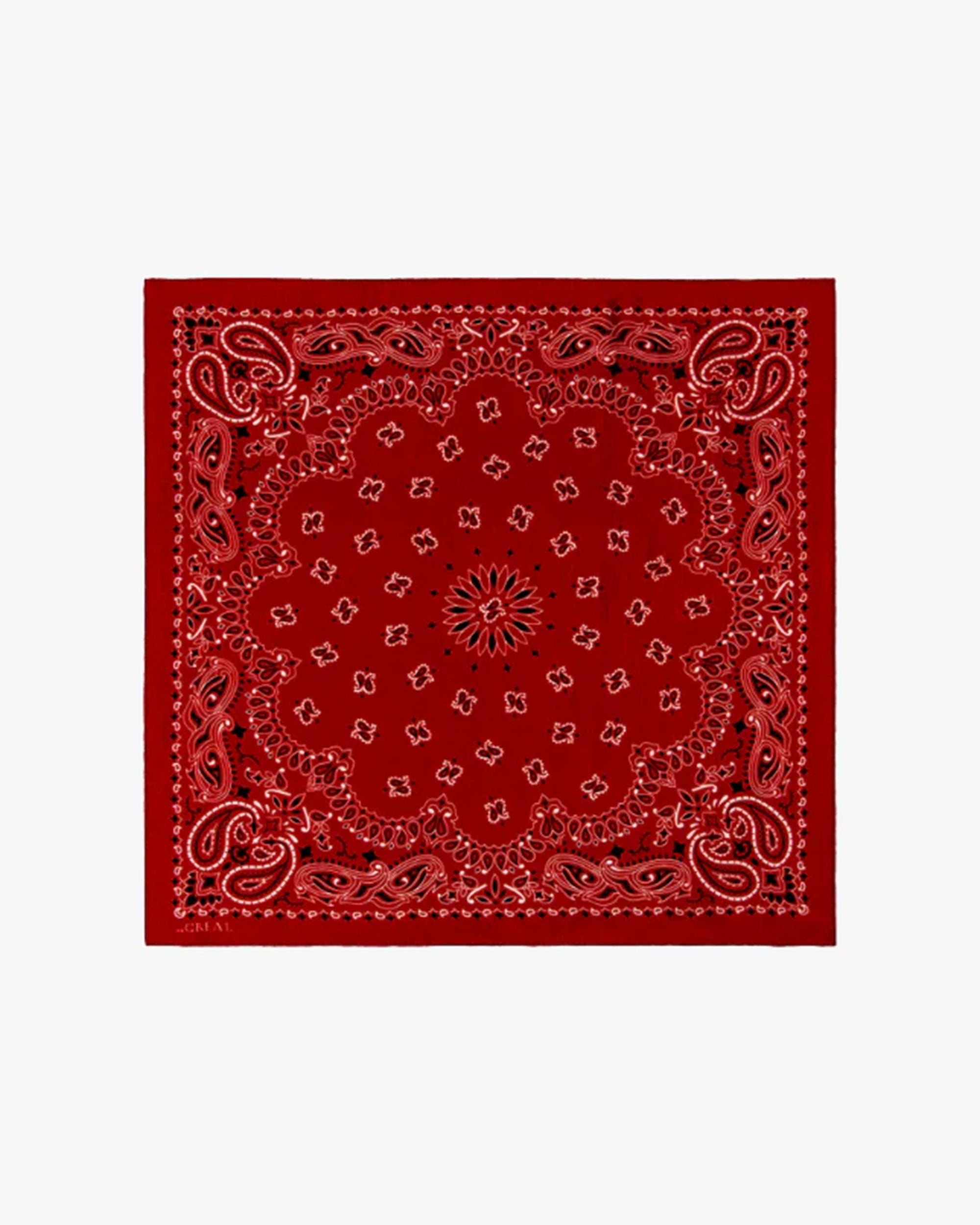 The Silk Bandana from The Great Inc. is a red silk accessory with classic white and black paisley patterns, including detailed symmetrical floral designs, shown on a plain white background.