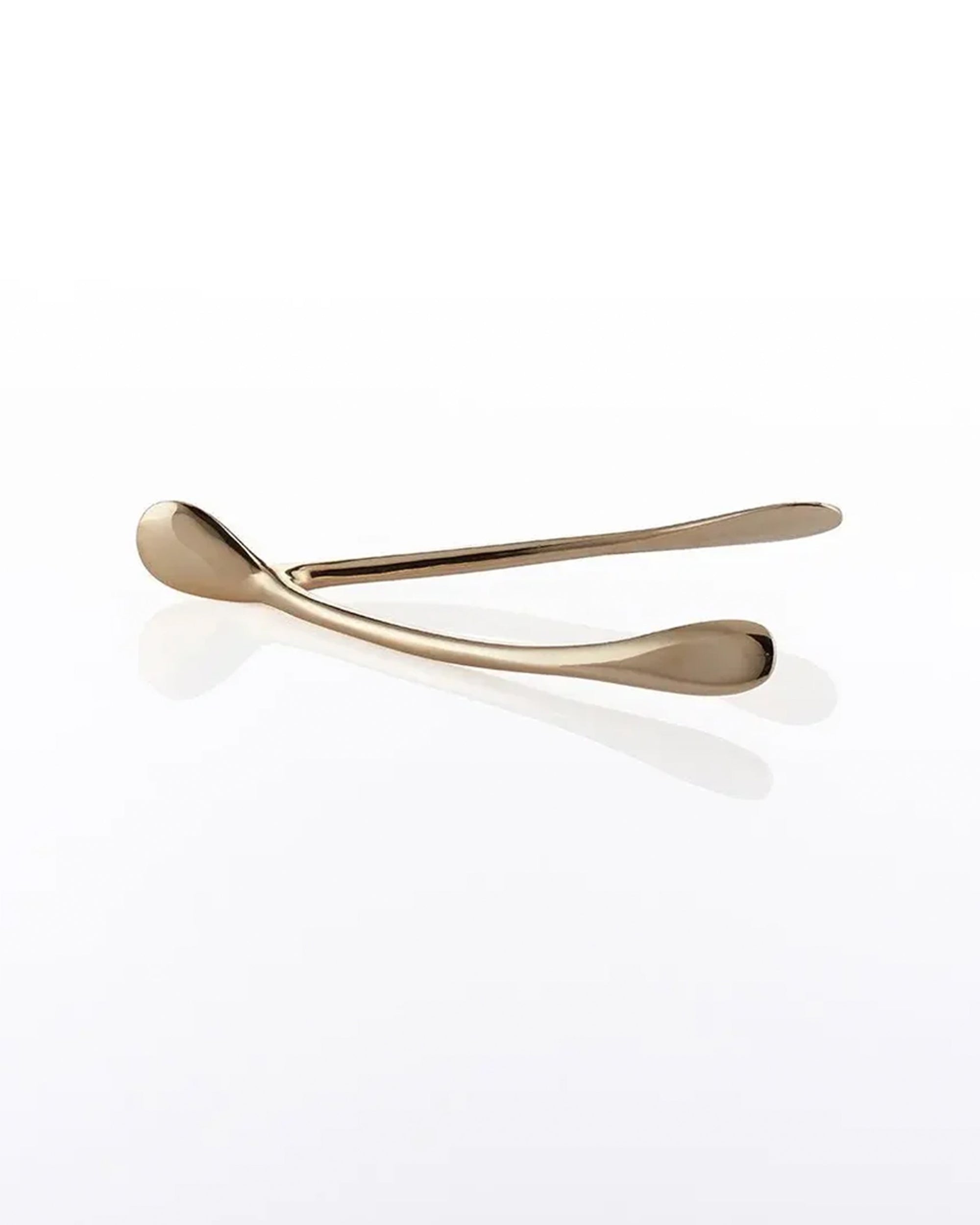 A metallic gold Wishbone /Small decor piece rests on a glossy white surface, casting a soft reflection—an elegant handcrafted aluminum accent.