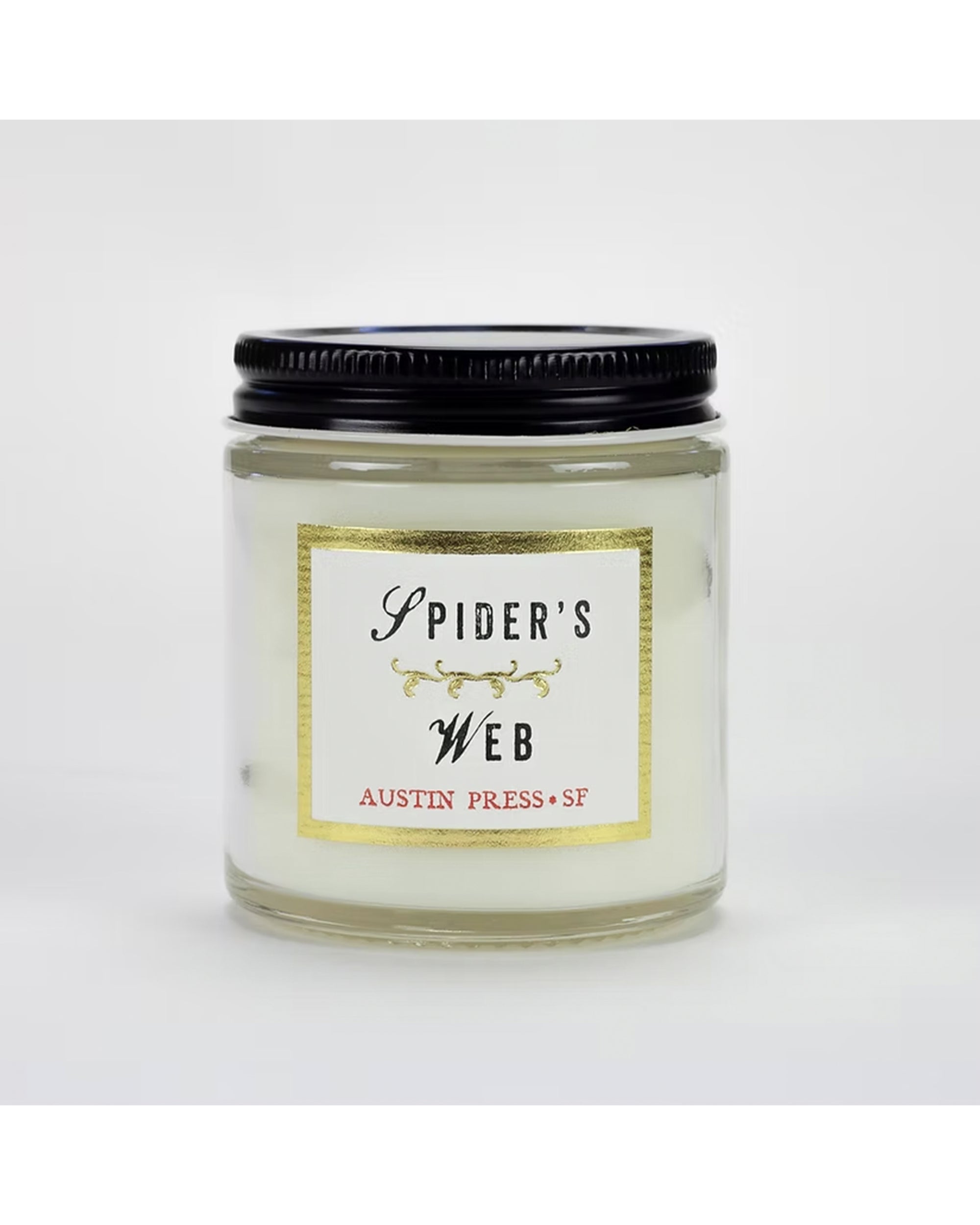A glass jar candle with a black lid labeled &quot;Austin Press Travel Candle&quot; features gold accents, &quot;Austin Press SF,&quot; and contains white botanical waxes for an all-natural experience. Brand: Faire.