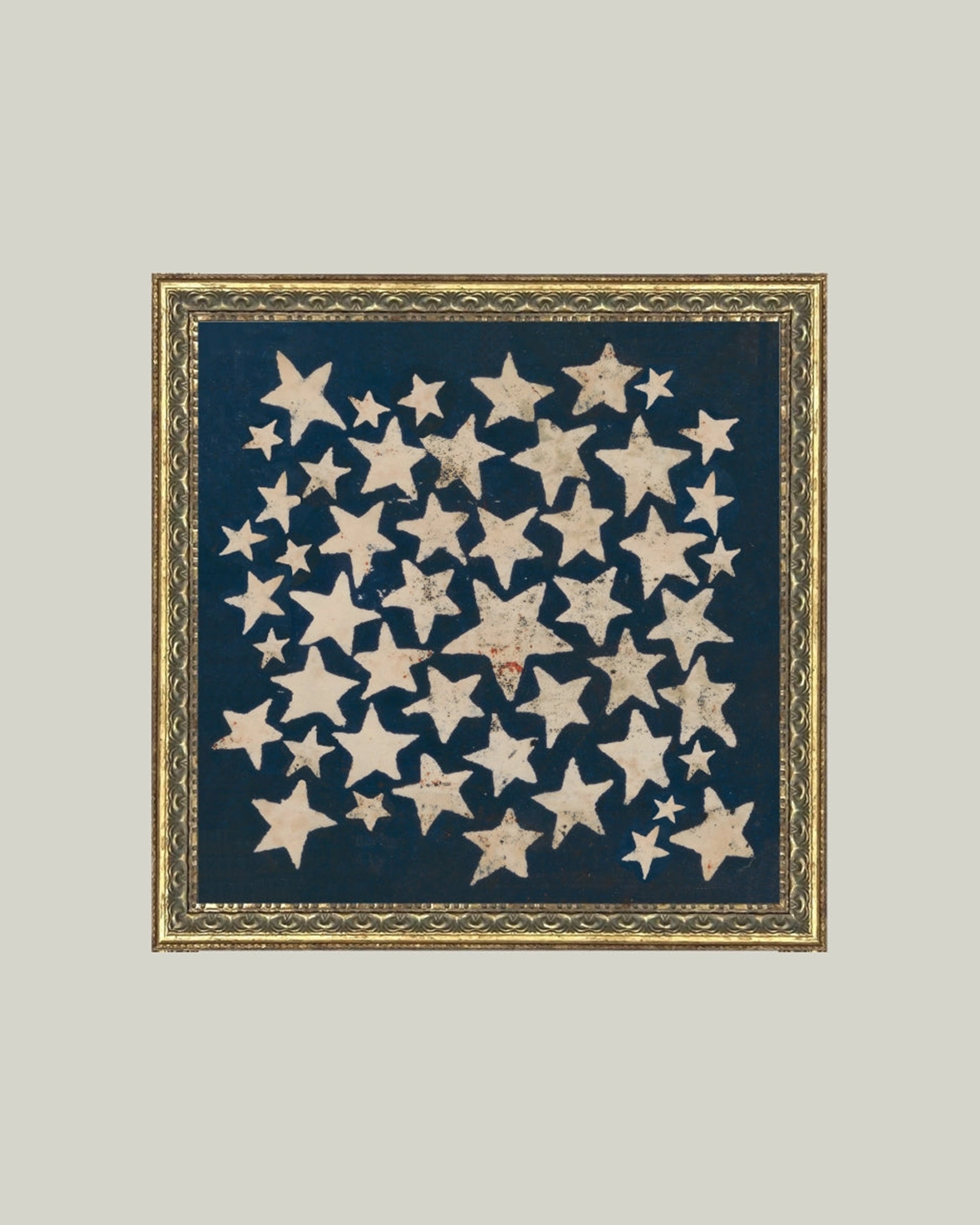The Stars Framed Art by Petal Lane Home displays off-white stars of varying sizes in a loose circle on a navy background, presented in a handcrafted ornate frame for an elegant touch.