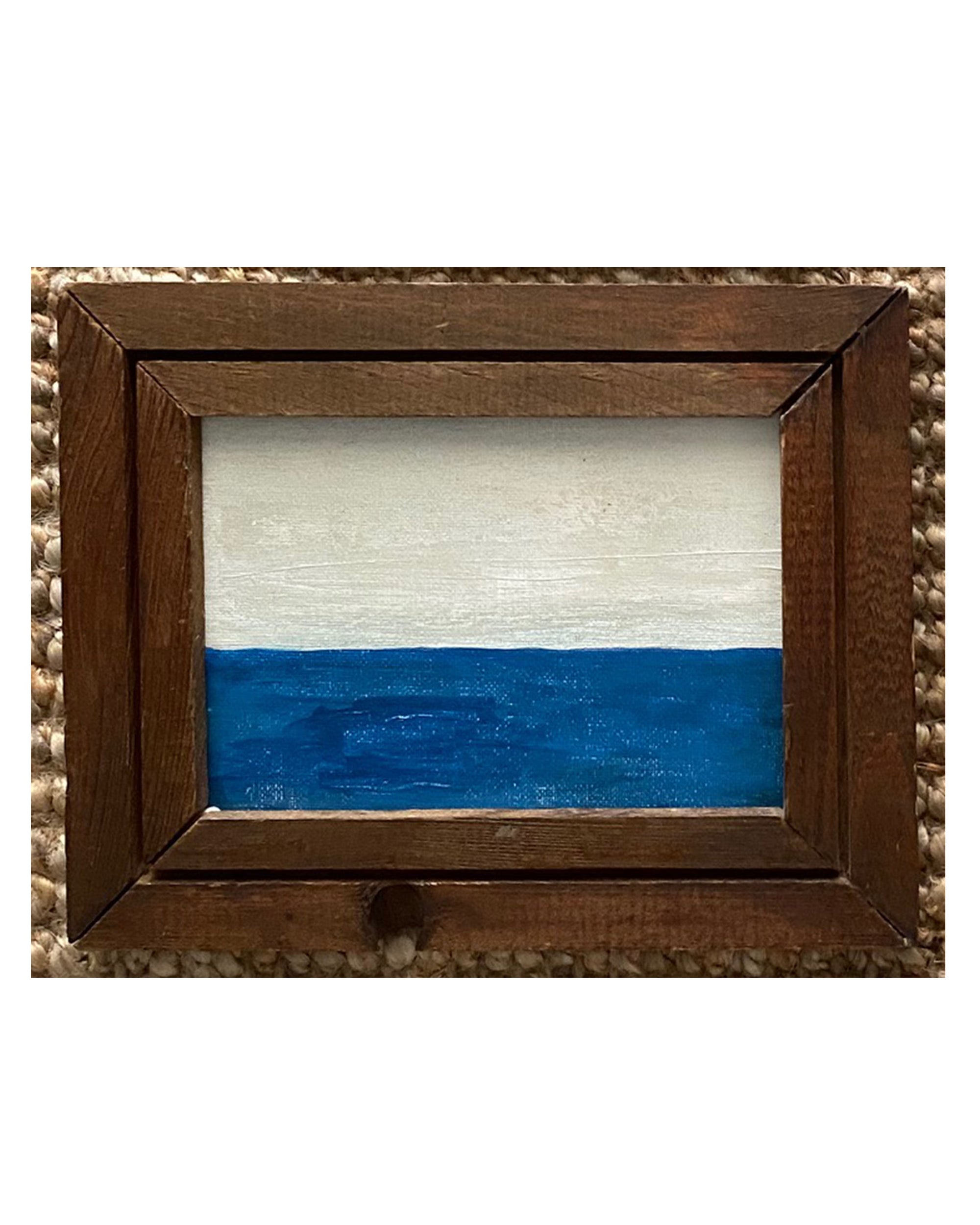 SKY & STARS by Tak Design is a small hand-painted art piece with a simple design—white on top, solid blue on the bottom, divided by a straight line—set in a rustic dark wood frame for vintage charm.