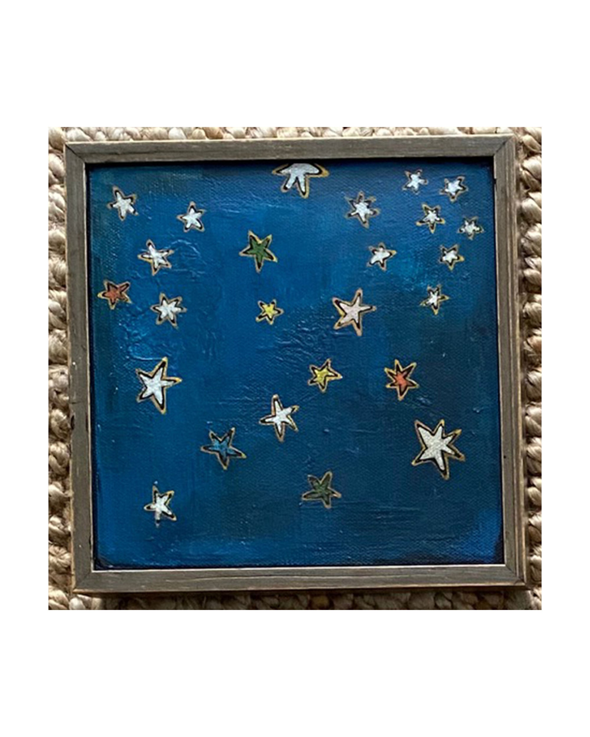 SKY & STARS by Tak Design is a framed, hand-painted art piece depicting a dark blue night sky with colorful stars. Set in a vintage frame, this local artist’s creation is displayed on a woven-textured surface.
