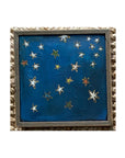 SKY & STARS by Tak Design is a framed, hand-painted art piece depicting a dark blue night sky with colorful stars. Set in a vintage frame, this local artist’s creation is displayed on a woven-textured surface.