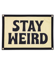 The Oxford Pennant Stay Weird Camp Flag 16x24 features bold black "STAY WEIRD" text on a cream background with a black border and metal grommets, making it perfect wall decor to energize any space.