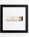 A matchbox labeled "Stein Eriksen Lodge Deer Valley" is centered within a Art Square Black Frame against a white background. The matchbox is beige with a gold design and contains black-tipped matches.