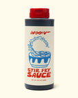 A 15.5 oz bottle of Faire’s Woon Stir Fry Sauce with a red cap, blue noodle bowl illustration, and red “WOON” and “STIR FRY SAUCE” text on the label. Gluten-free cooking sauce.