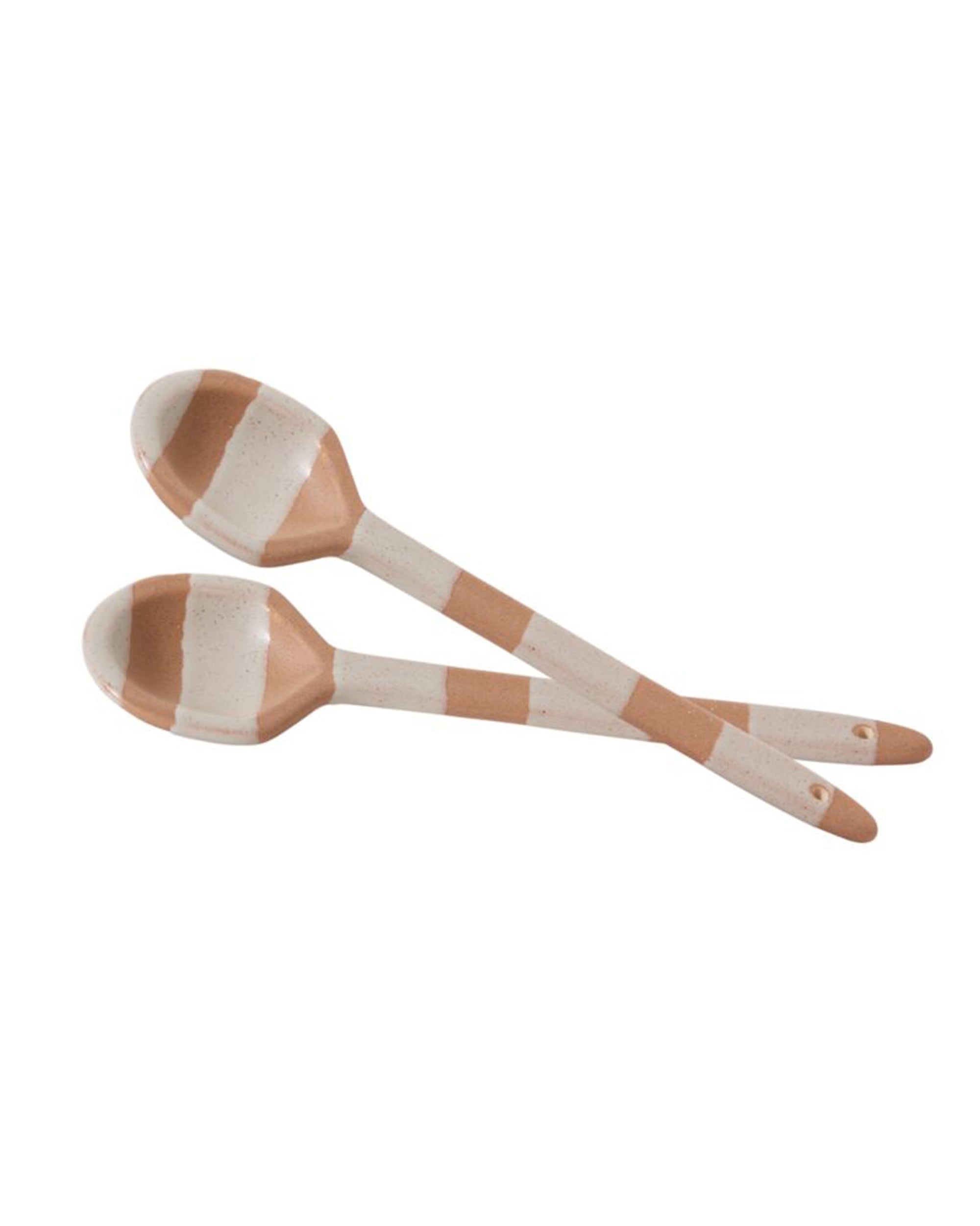 Two 50421 Botera Spoons with a cream and brown striped pattern are crossed on a white background, highlighting their elegant ceramic form and minimalist design.