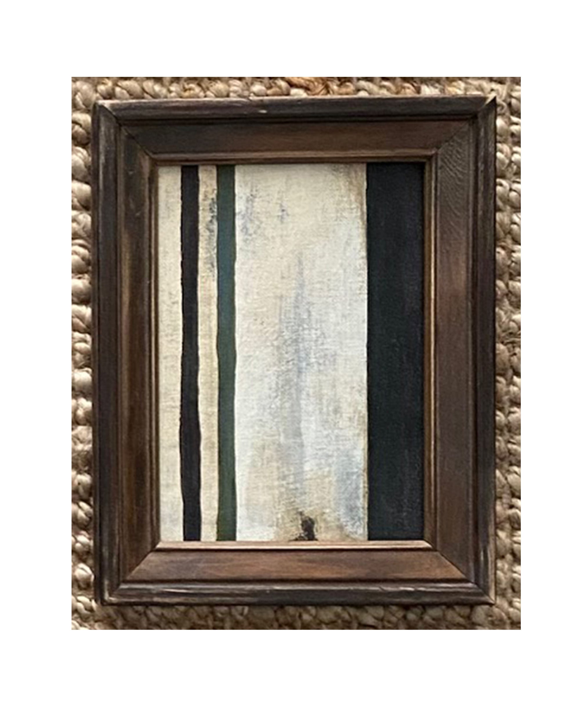 The STRIPES Framed Art by Tak Design features vertical black, dark green, and off-white stripes on a textured backdrop, accented with a thick wooden frame and displayed against a woven surface.