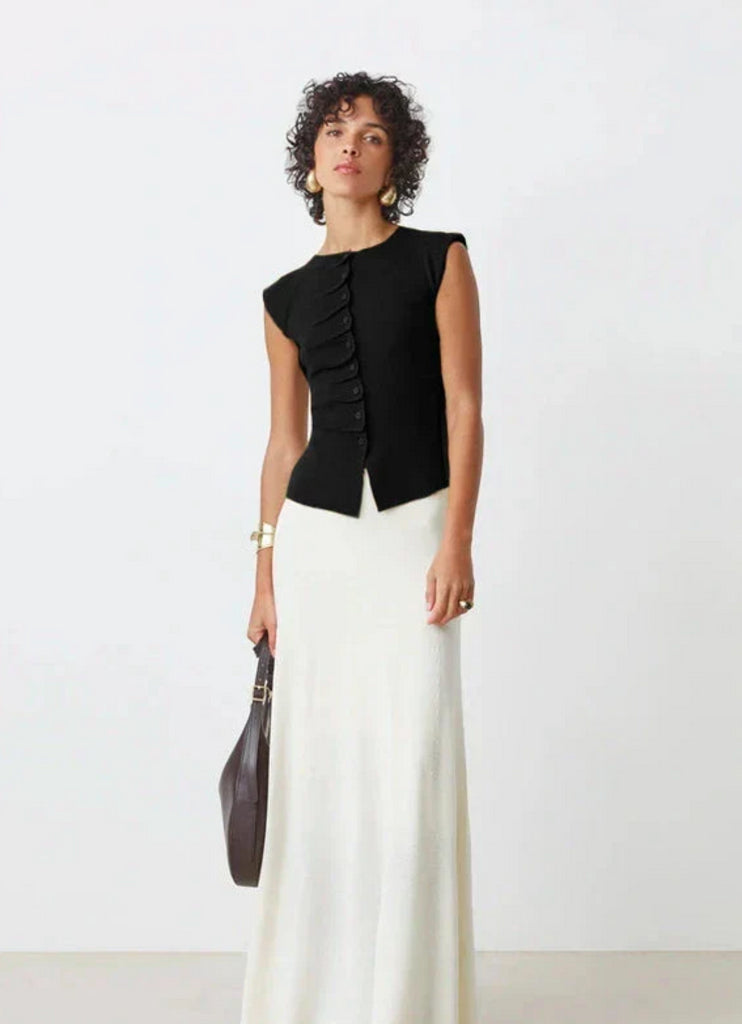 A woman wearing the SUNCOO PAGNI S/L button front black jumper over a white skirt.