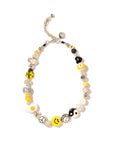 The Sunny Side Necklace 16" by Venessa Arizaga is a playful piece with silver, white, black, and yellow beads, smiley faces, yin-yang symbols, numbers, peace signs, fried egg motifs, and metallic accents on an adjustable silver chain.