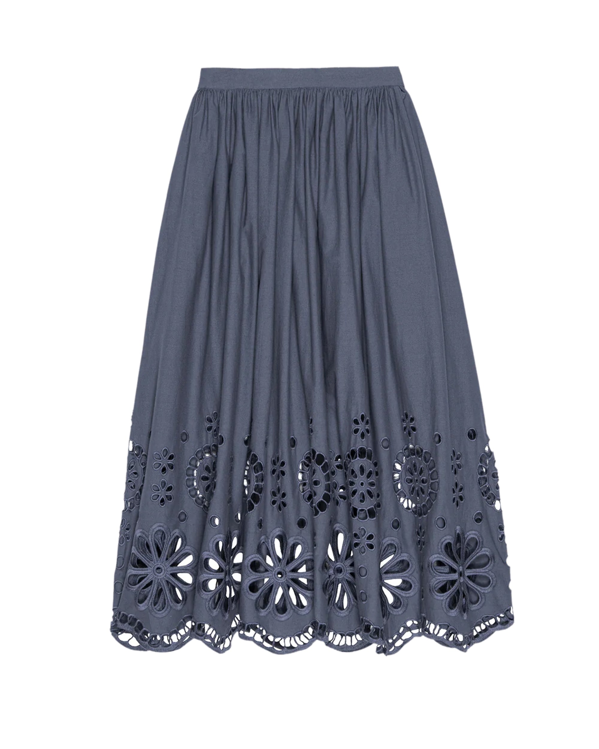 The Great Inc. Super Bloom Eyelet Skirt features a navy blue, knee-length design with a gathered waistband and Victorian-inspired floral eyelet cutouts along the lower half and scalloped hem.