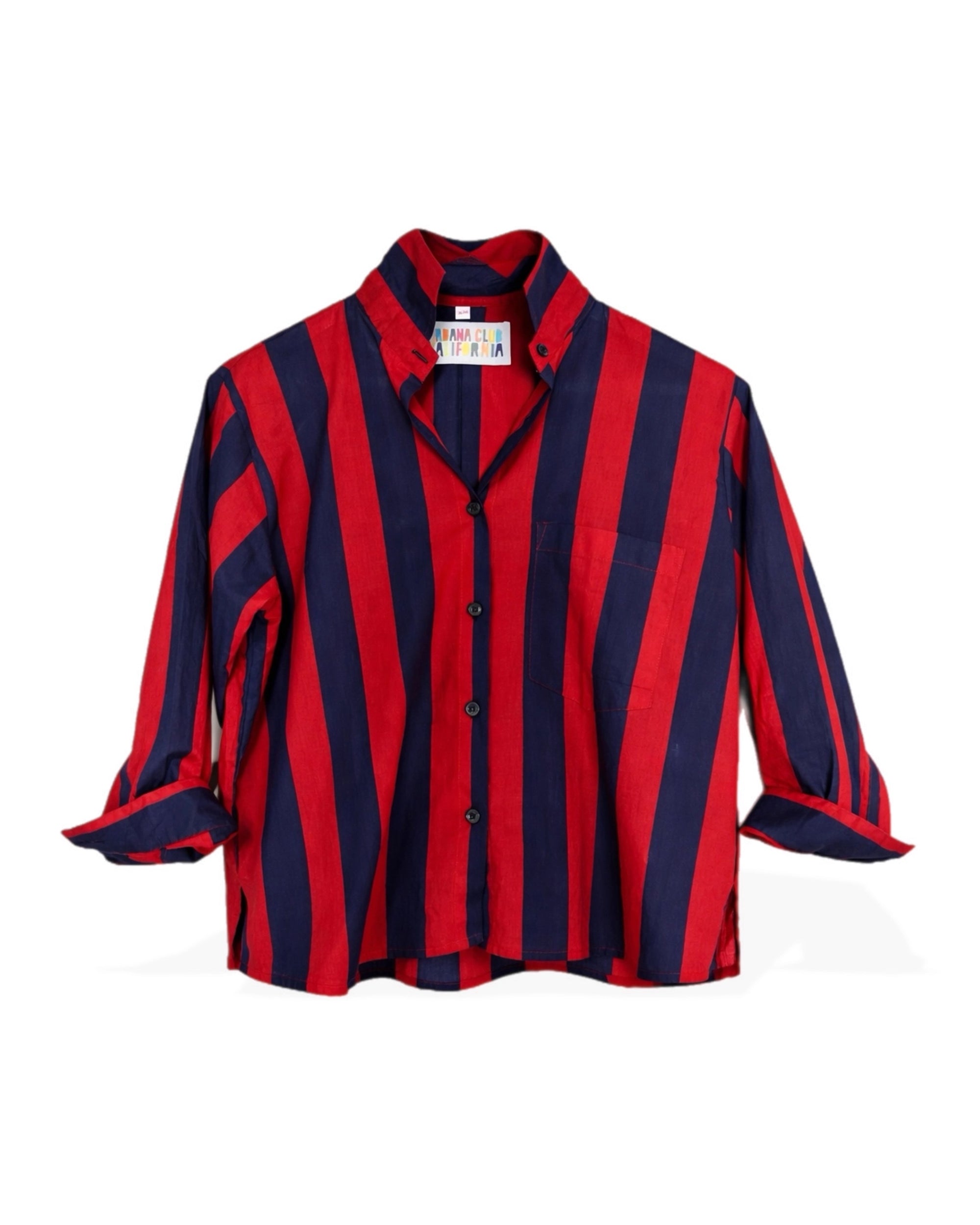 The Faire Surf Stripe Top is a long-sleeve, button-up shirt with bold vertical red and navy stripes, a collar, chest pocket, rolled sleeves, and a cropped silhouette made from lightweight cotton.
