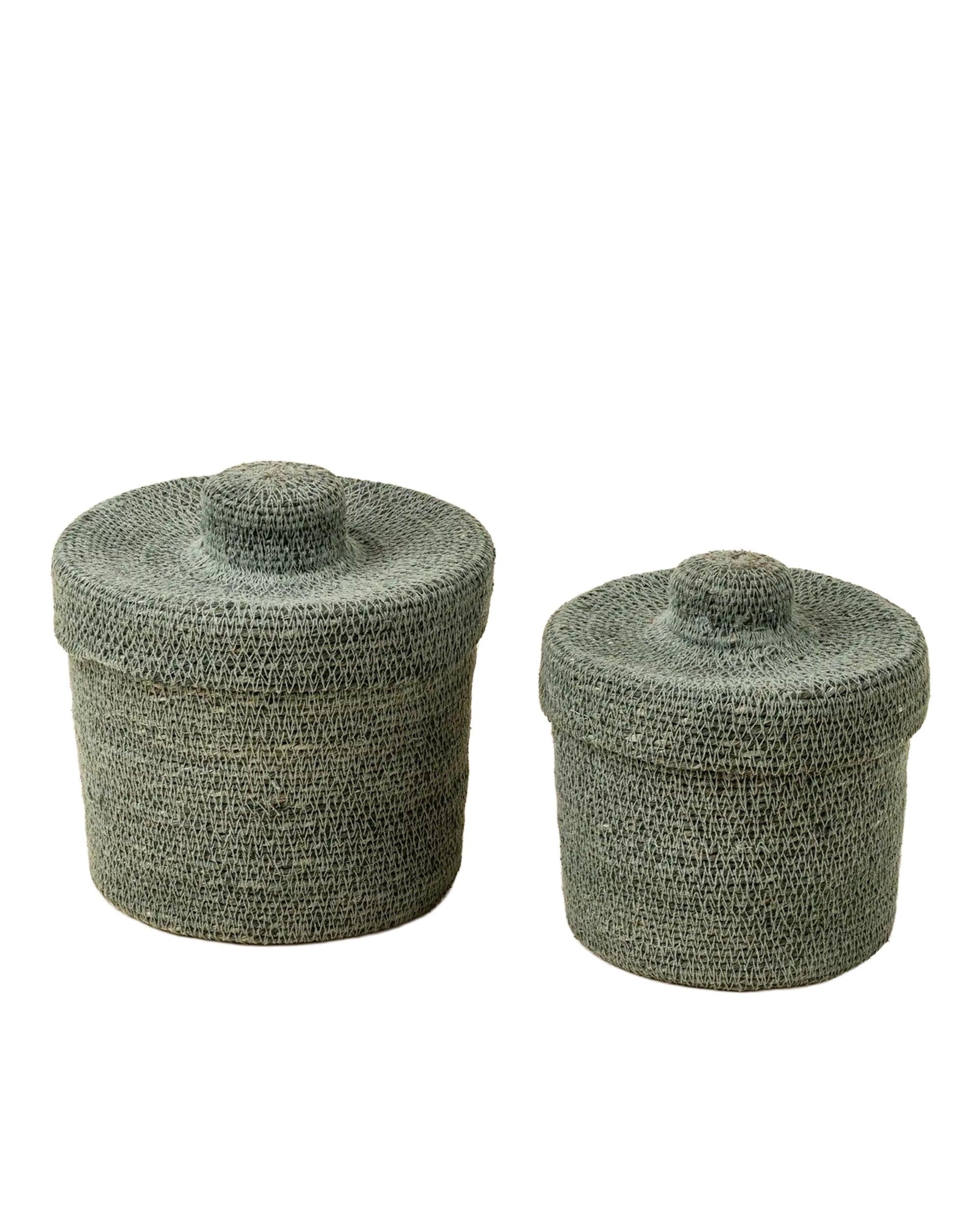 Two round green Indaba Tajine Seagrass Baskets with lids, one large and one small, add Moroccan-inspired style and storage when placed side by side on a white background.