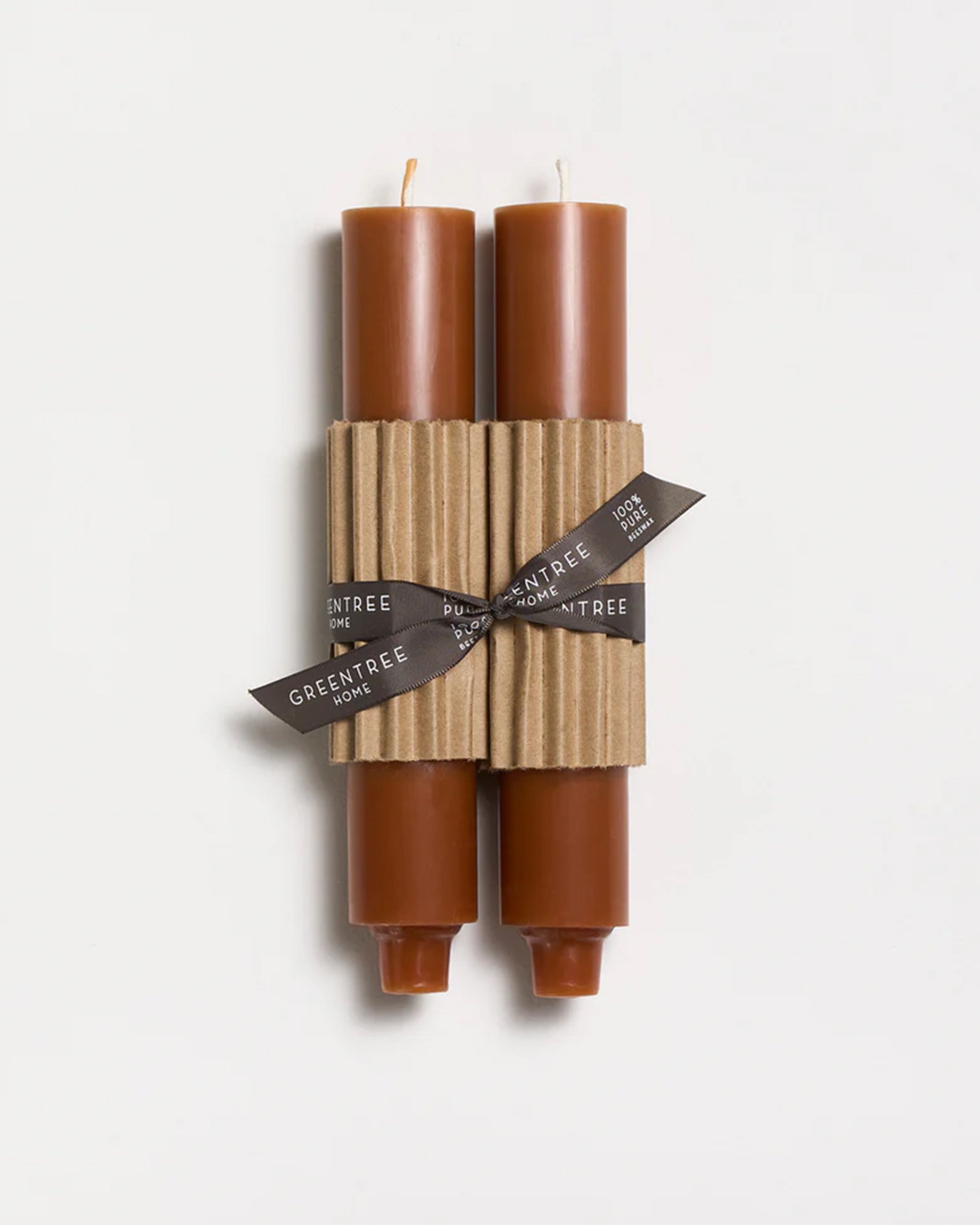 Two terra-cotta 9" taper candles from Faire are hand poured, wrapped together with a ribbed cardboard sleeve, and tied with a black ribbon displaying the brand name, set against a plain white background.