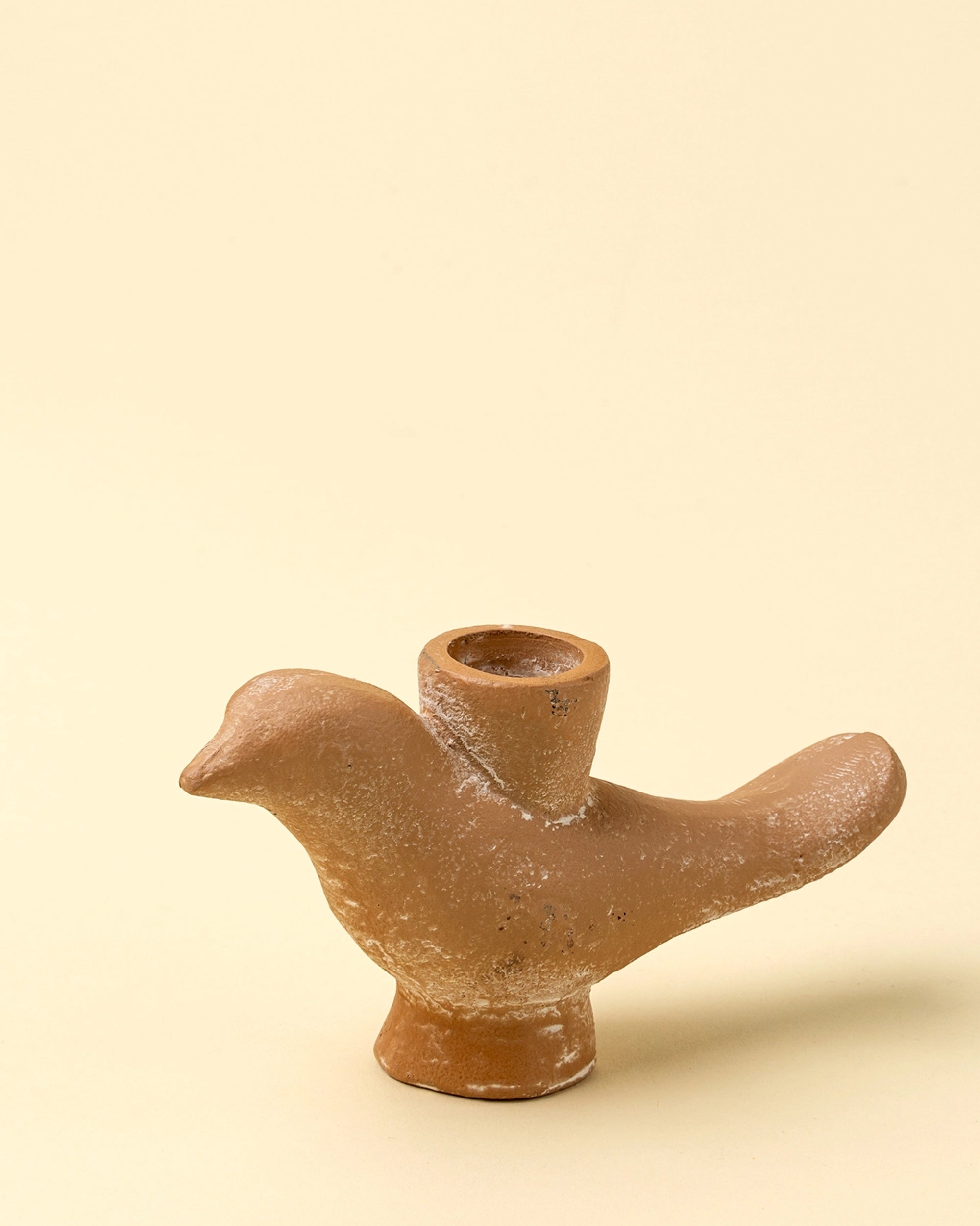 The Indaba Wren Candle Holder is a small, brown, ceramic bird-shaped piece with a round back opening, perfect for adding rustic charm to your decor. Shown here against a plain beige background.