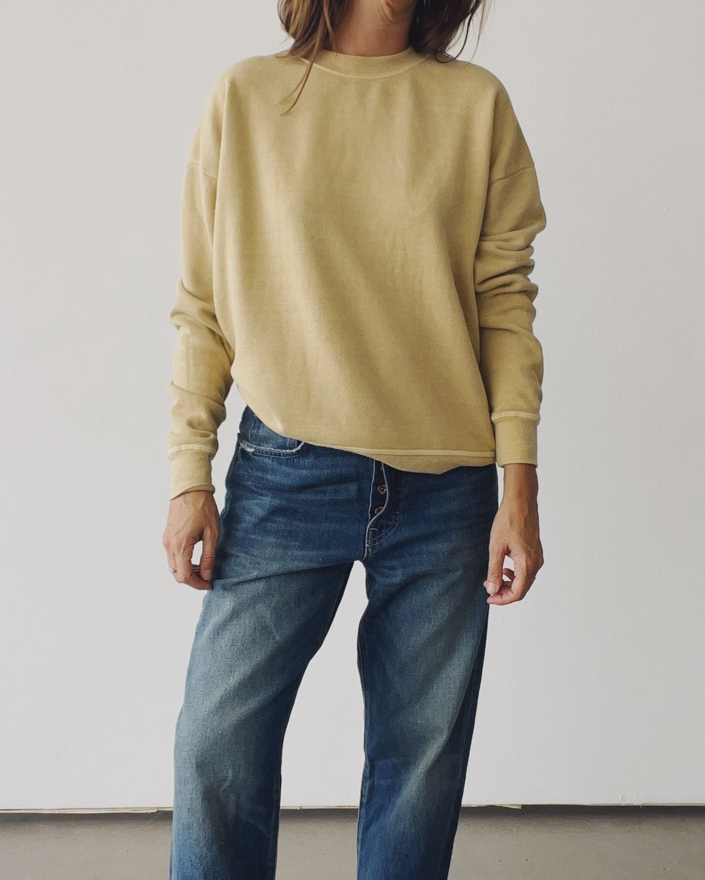 Wearing The Sweatshirt 26 by Hey Gang with blue jeans, a person stands against a plain white background. Their head is out of the frame and their arms are relaxed at their sides.