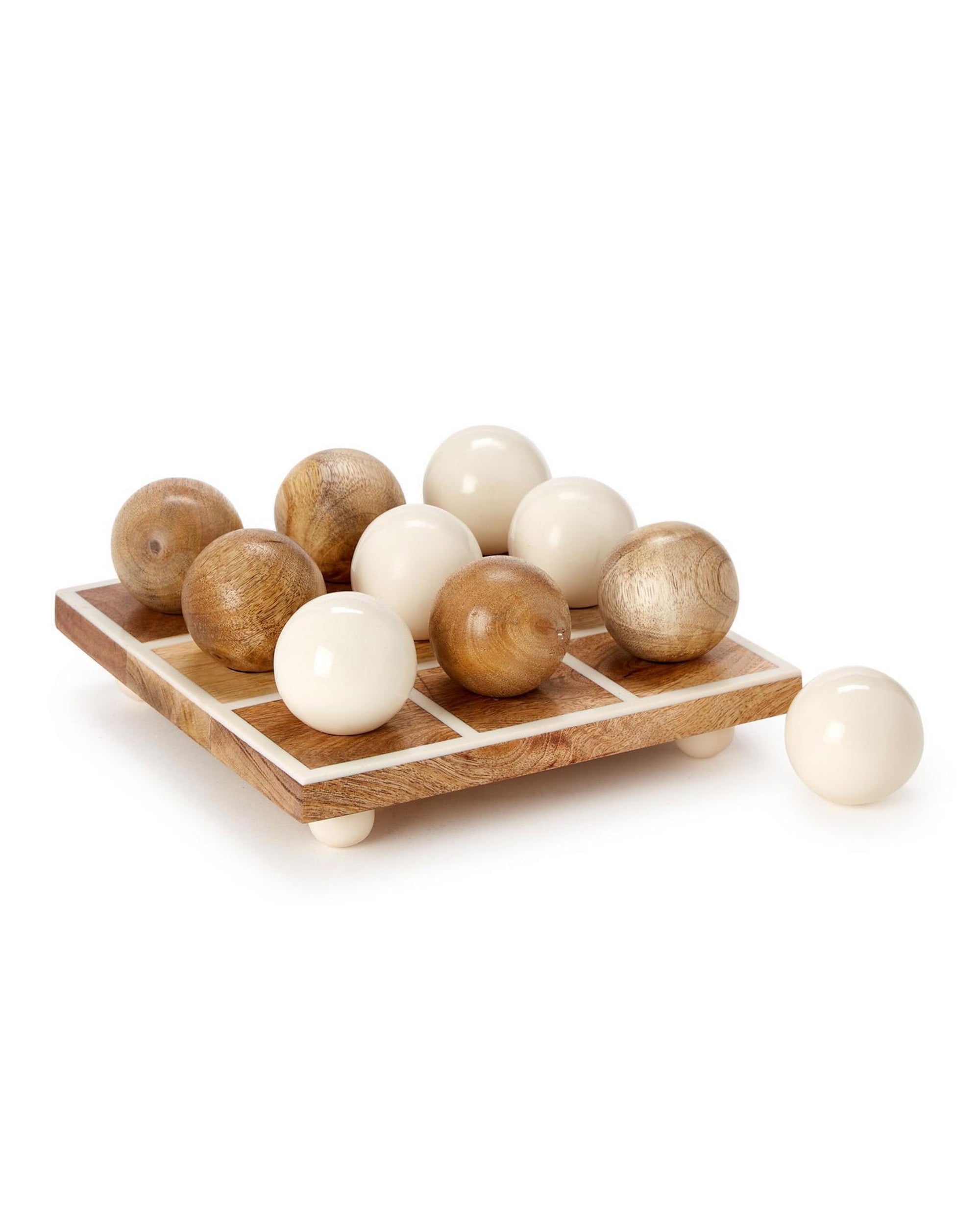The Two's Company Tic Tac Toe Game features a hand-crafted mango wood board, five light-colored wooden balls, and five glossy white balls (with one off the board)—a stylish addition to any game room.
