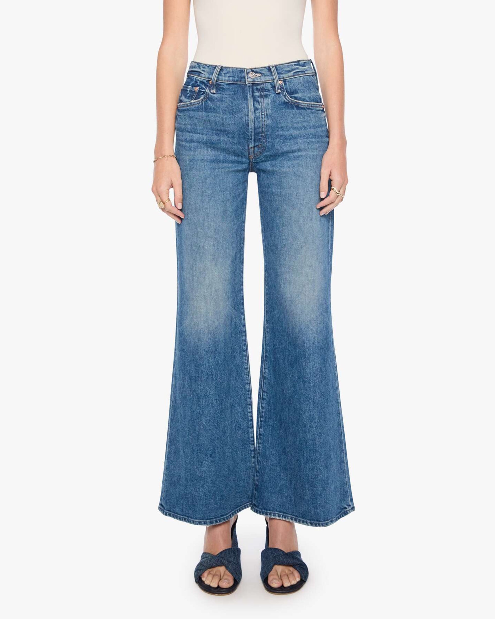 The Tomcat Roller Sneak jeans by Mother styled with a white top and black sandals for a vintage denim look.