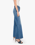 Mother’s The Tomcat Roller Sneak jeans in blue denim, styled with a white top and heeled sandals, side view.