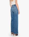 The Tomcat Roller Sneak jeans by Mother in blue denim, styled with a white tank and heels, shown from the back.