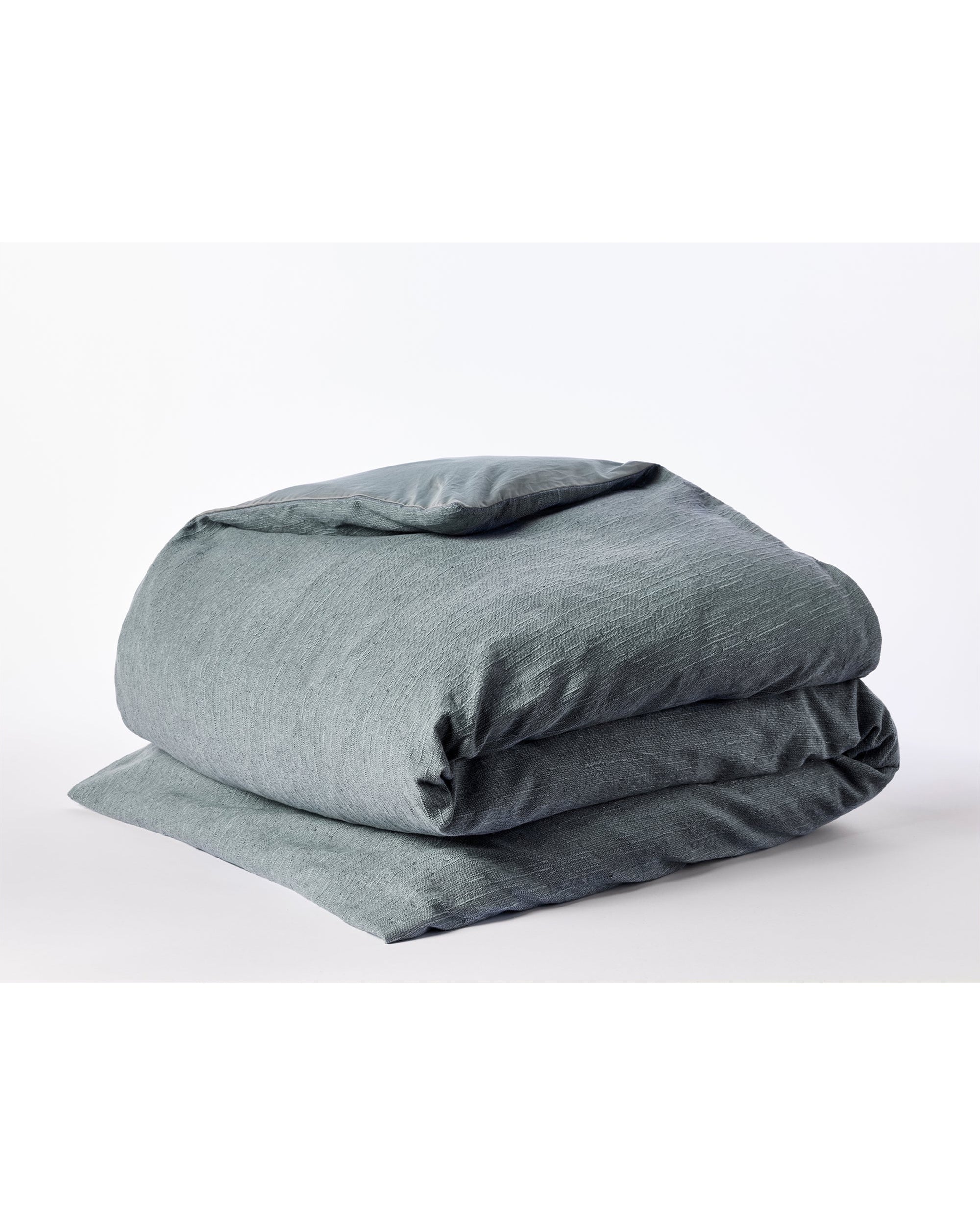 The Toro Canyon Org. Duvet Cover Marine King by Coyuchi Inc is shown neatly folded on a white surface, highlighting its soft organic cotton and subtle textured weave in a soothing gray-blue tone.