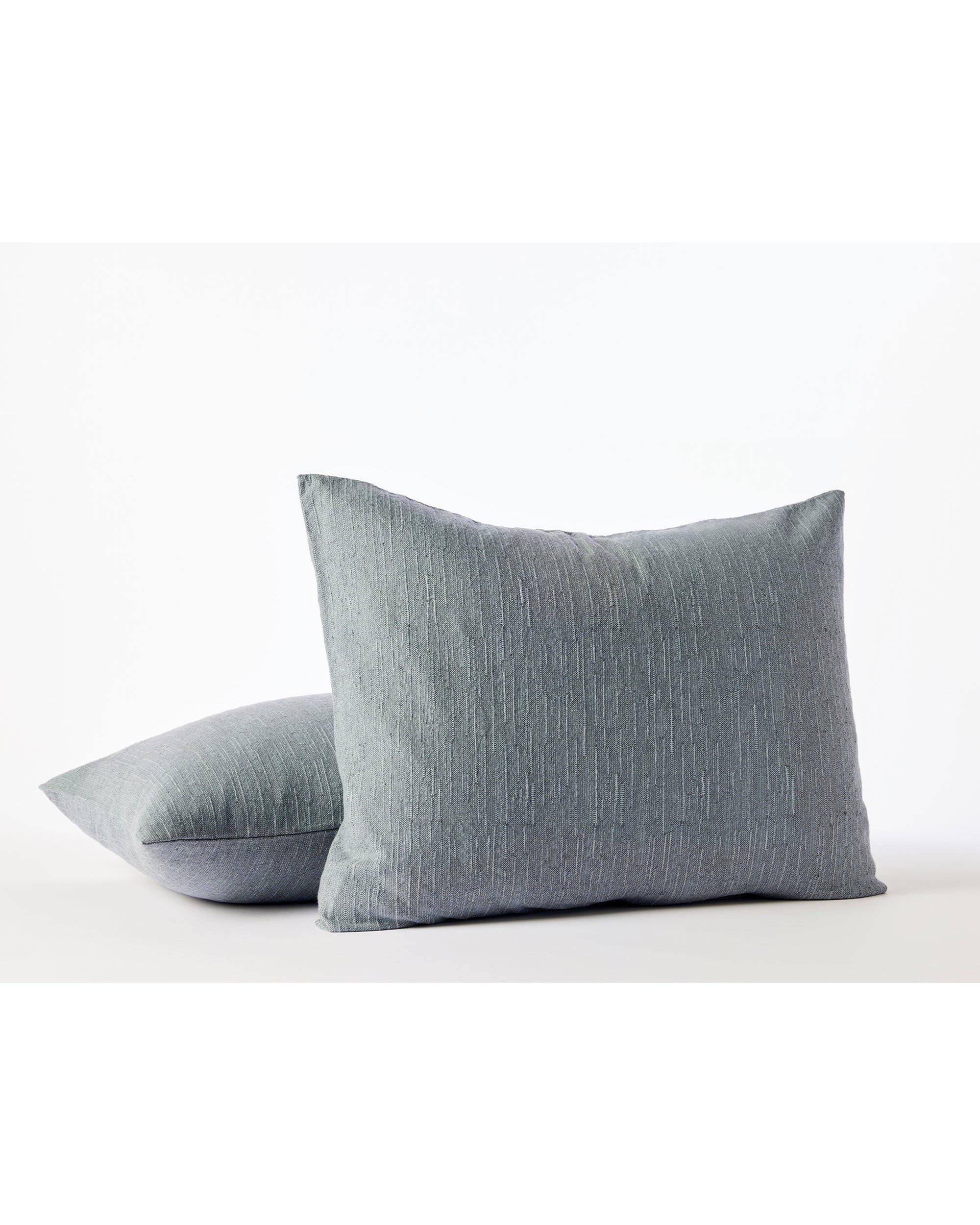 Two Toro Canyon Org Euro Shams in Marine by Coyuchi Inc are displayed on a white surface—one upright, the other flat and slightly overlapping—showcasing textured details and mid-century weaving inspiration against a plain white background.