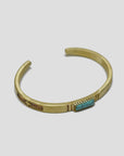 The MENS Turquoise Inlay Bracelet by Curated Basics is a handmade gold cuff with an open design crafted from solid brass. It highlights a vibrant turquoise stone at its center, complemented by subtle etched patterns on the metal against a plain white background.