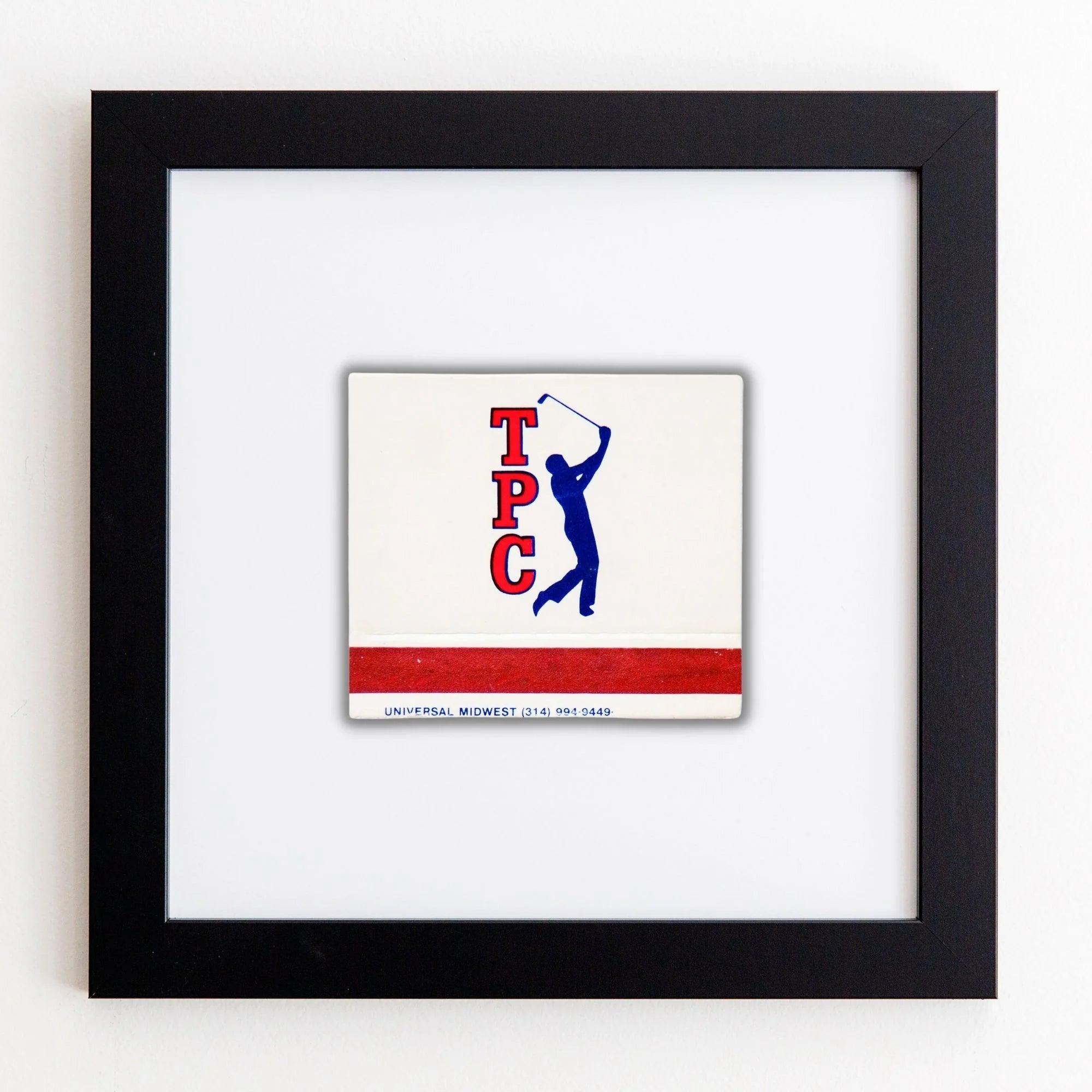 A framed acrylic print featuring a blue silhouette of a golfer in mid-swing, with the letters &quot;TPC&quot; in red and black and the text &quot;UNIVERSAL MIDWEST 06-21-3429&quot; below, displayed in an Art Square Black Frame by Match South.