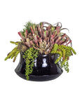 The Faire Tulip Planter, a glossy black ceramic pot, showcases a dense mix of succulent plants with green trailing strings and spiky red-tipped accents, creating a textured display against a white background.