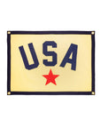 The Oxford Pennant USA Camp Flag 18x24 features a cream backdrop, navy border, bold navy "USA" lettering above a large red star, and gold grommets—ideal patriotic decor for any space.