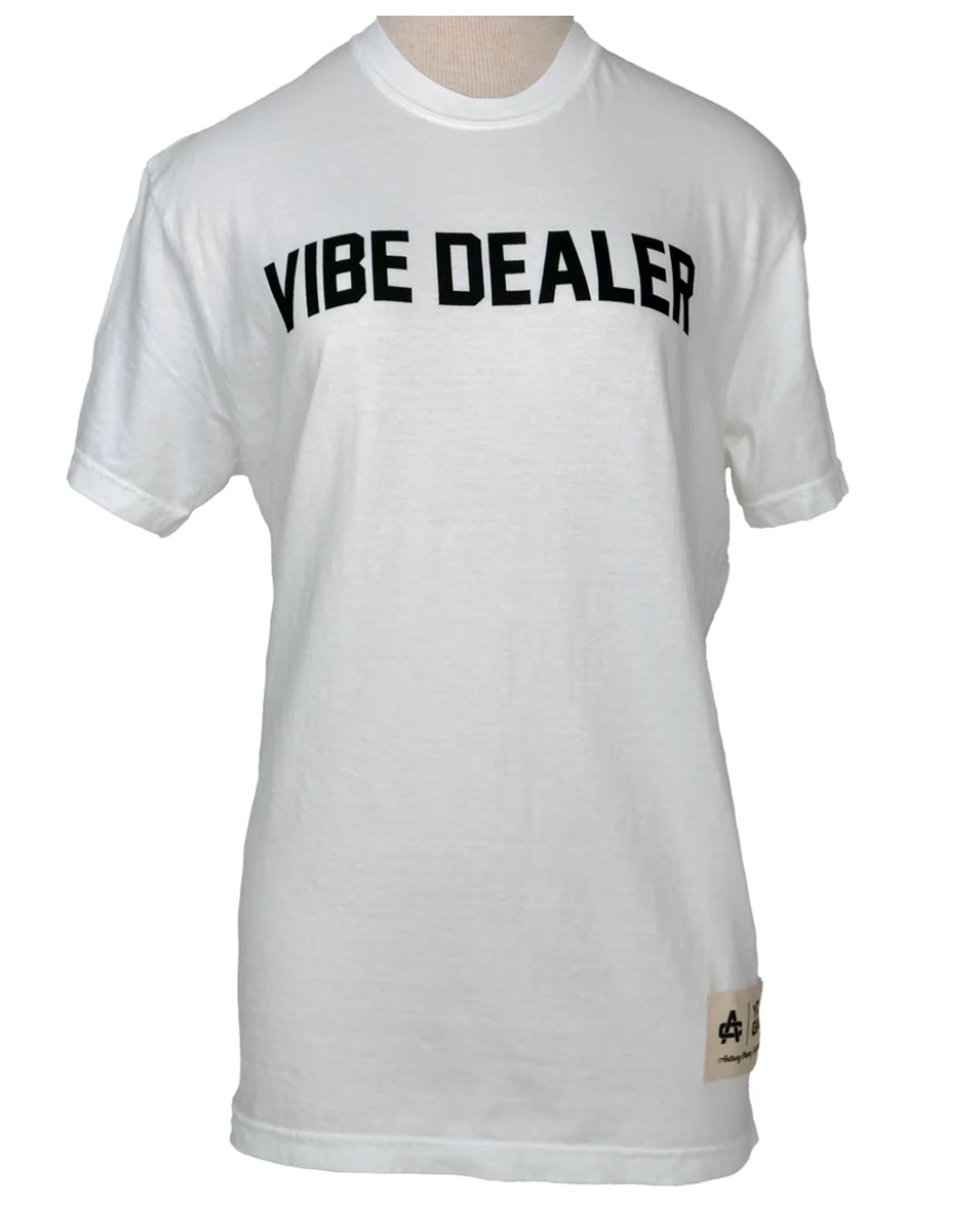 The VIBE DEALER Tshirt by Hype Factory Inc. is a white, vintage-washed 100% cotton unisex tee with "VIBE DEALER" in bold black text on the chest and a small beige tag near the hem.