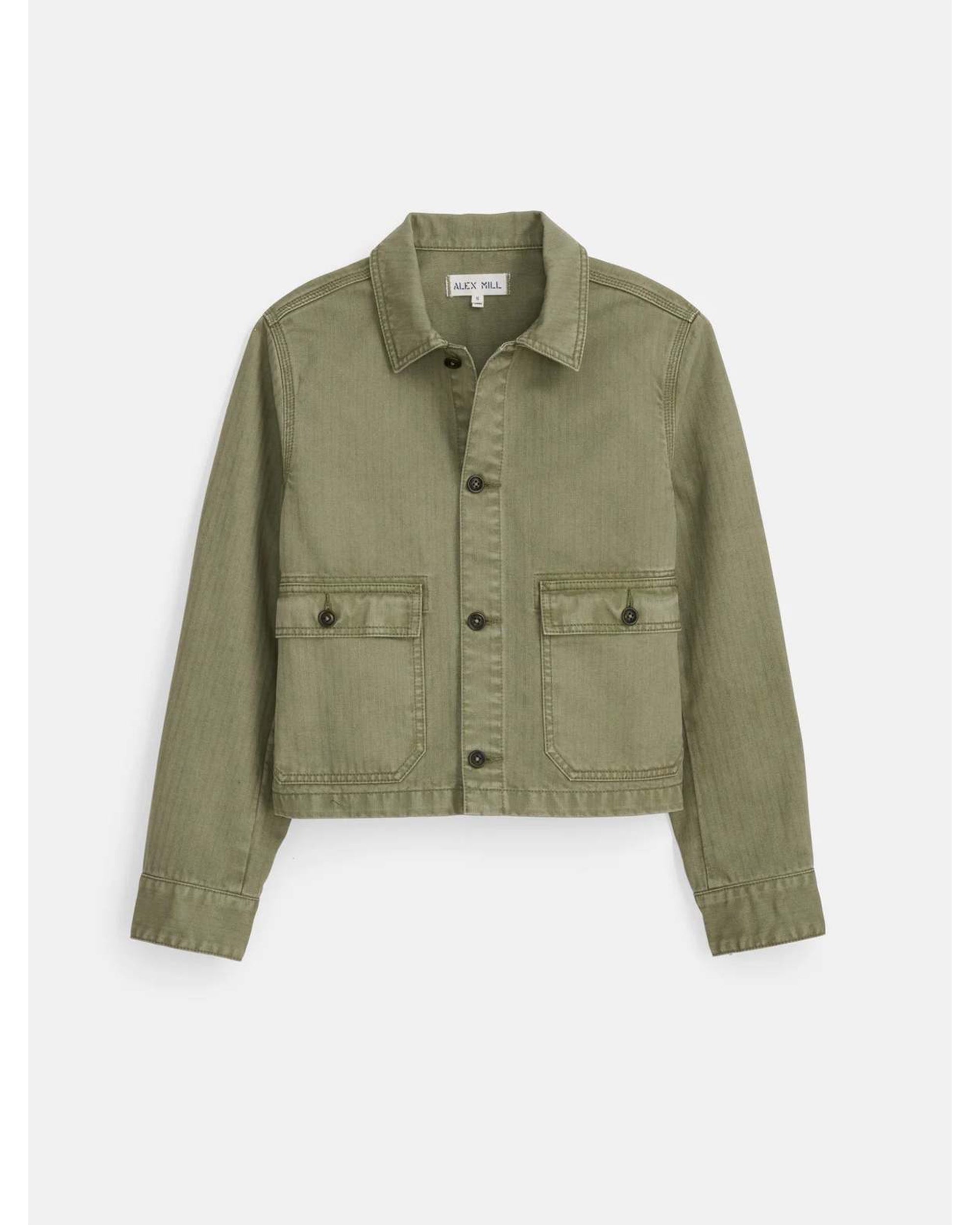 The Alex Mill Marfa Work Jacket is a cropped, light olive-green denim jacket with a relaxed fit, classic collar, button-up front, long sleeves, and two buttoned flap chest pockets, shown against a plain white background.