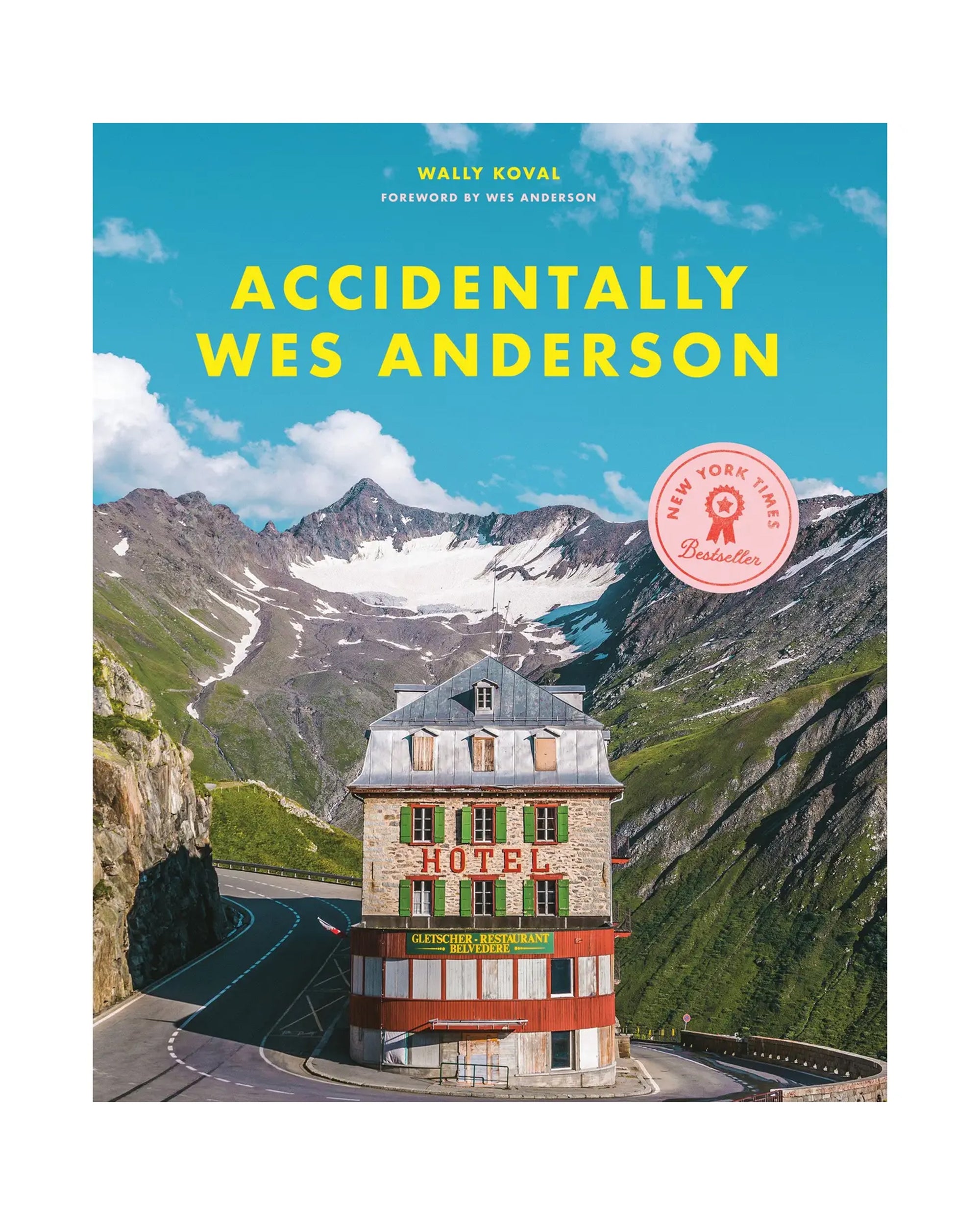 Book cover of "Accidentally Wes Anderson" by Faire, a travel book featuring a quirky hotel on a mountain road with snow-capped peaks in Wes Anderson’s style, plus a red "New York Times Bestseller" badge.