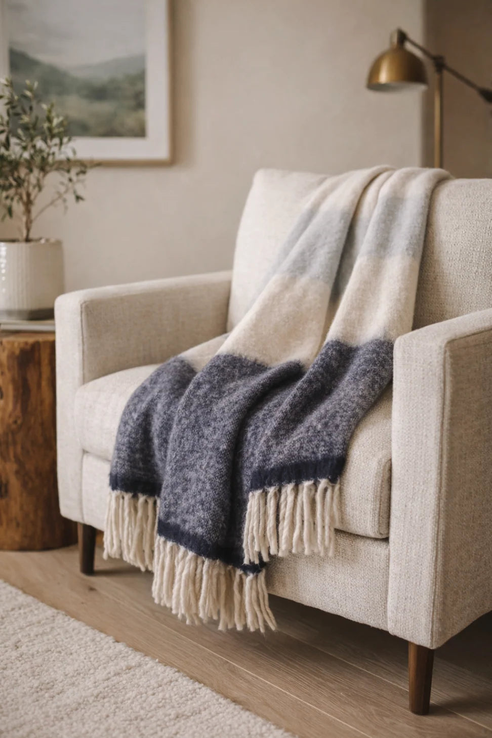Cream armchair with POM POM Whistler Throw in a softly lit cozy living room, Bungalow Furniture &amp; Accessories.