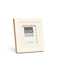 The 4x4 Floral Resin Frame by BIDK Home is a square, cream-colored photo frame with scalloped edges and a 4" x 4" display area, ideal for adding charm to your home decor.